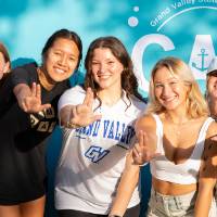 six students posing in front of CAB backdrop at Laker Kickoff photo booth giving anchor up signs